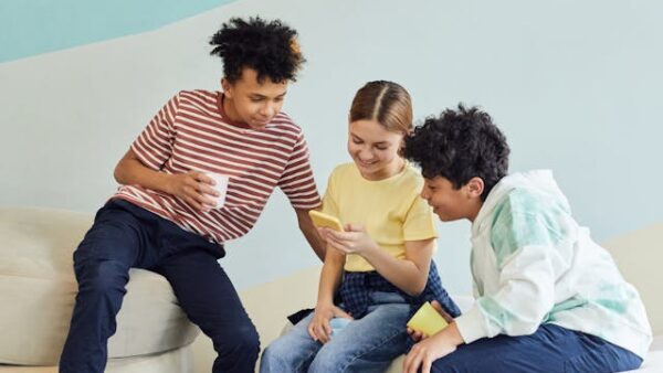 Three kids looking into phone together - Social Kids