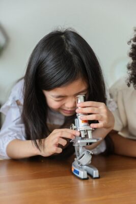 Science at school - girl looks into microscope