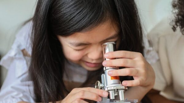Science at school - girl looks into microscope