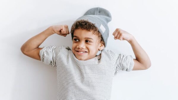 Child with hat poses with his 'muscles'for power kids